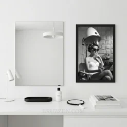 Cinematic salon fashion art in a black frame hanging on a minimalist living room wall above a sofa.