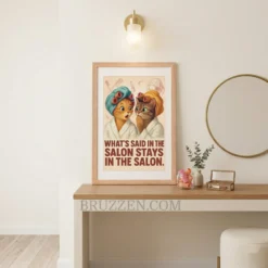 Funny vintage cat art framed on a warm peach accent wall in a cozy living room next to a velvet armchair.